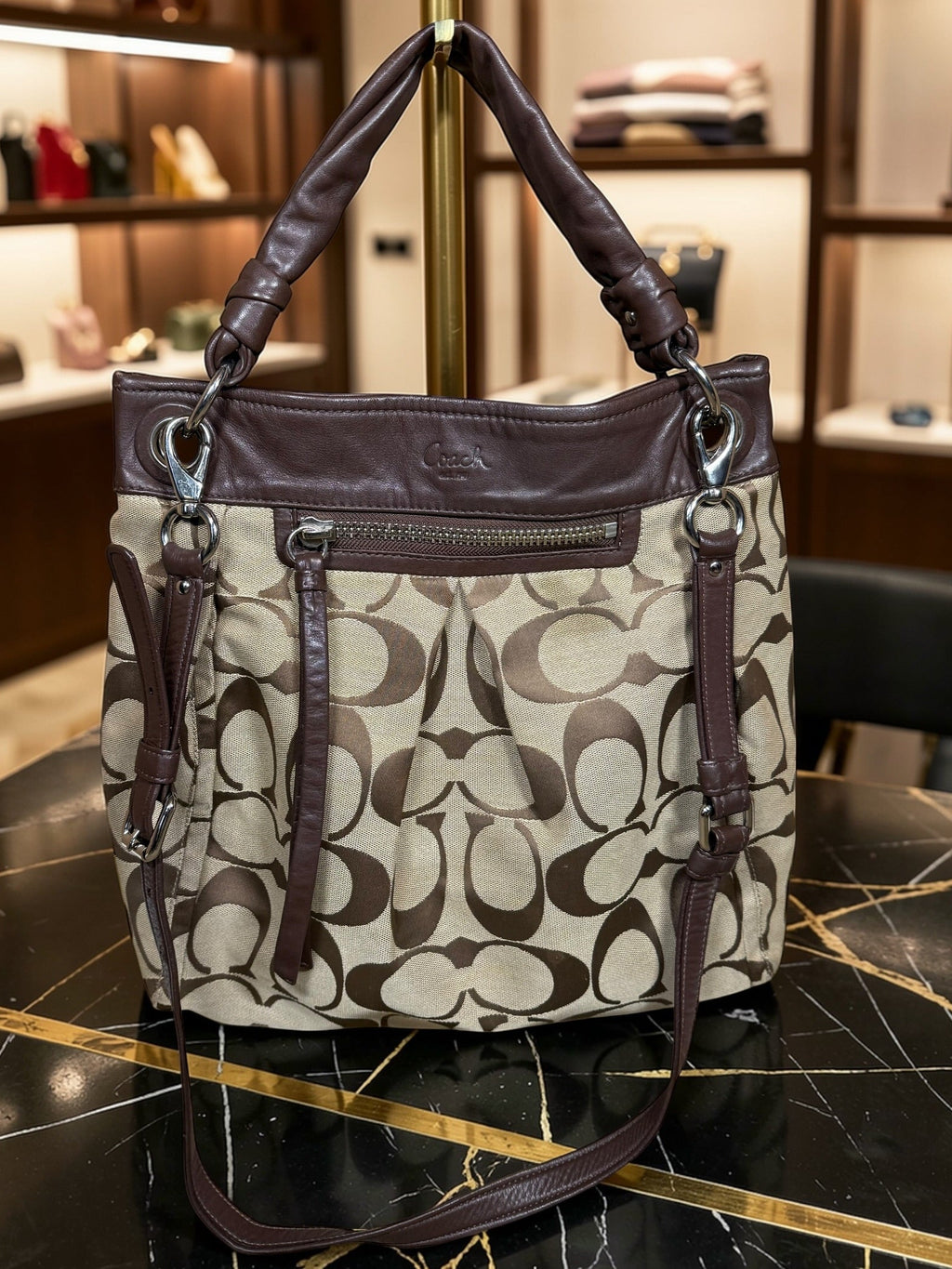 Coach handbag with brown and beige pattern on a marble surface