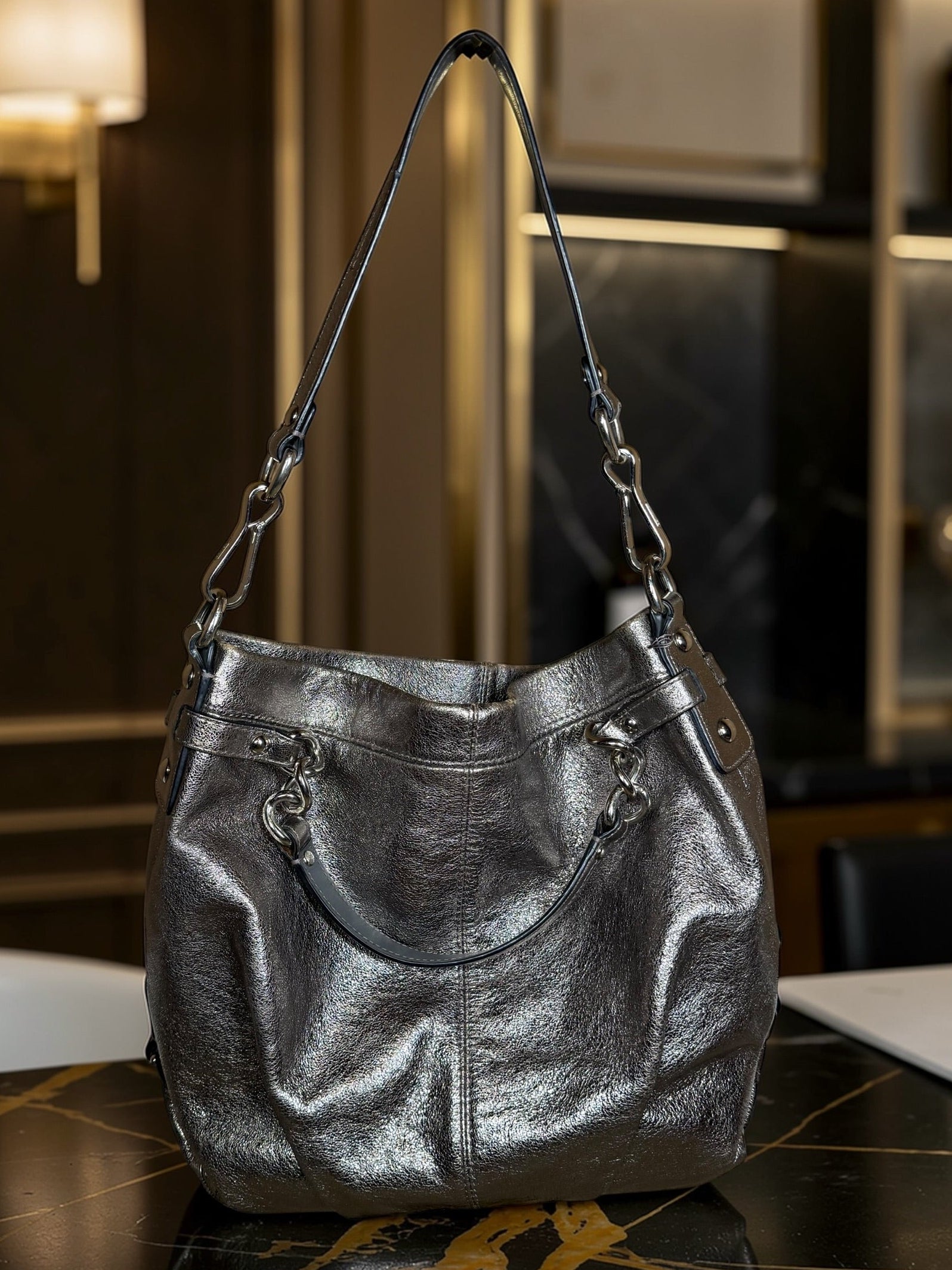 Silver handbag on a marble surface with a blurred indoor background
