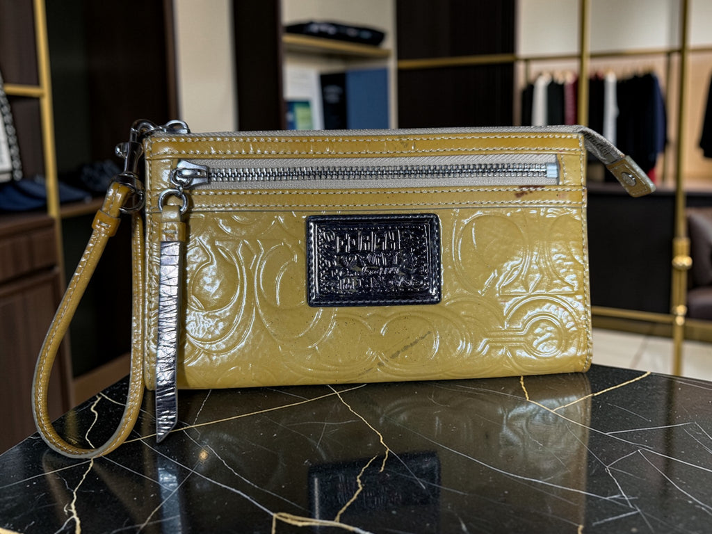 Grand porte-monnaie de poignet Coach Poppy en cuir verni jaune moutarde avec motif « C » embossé