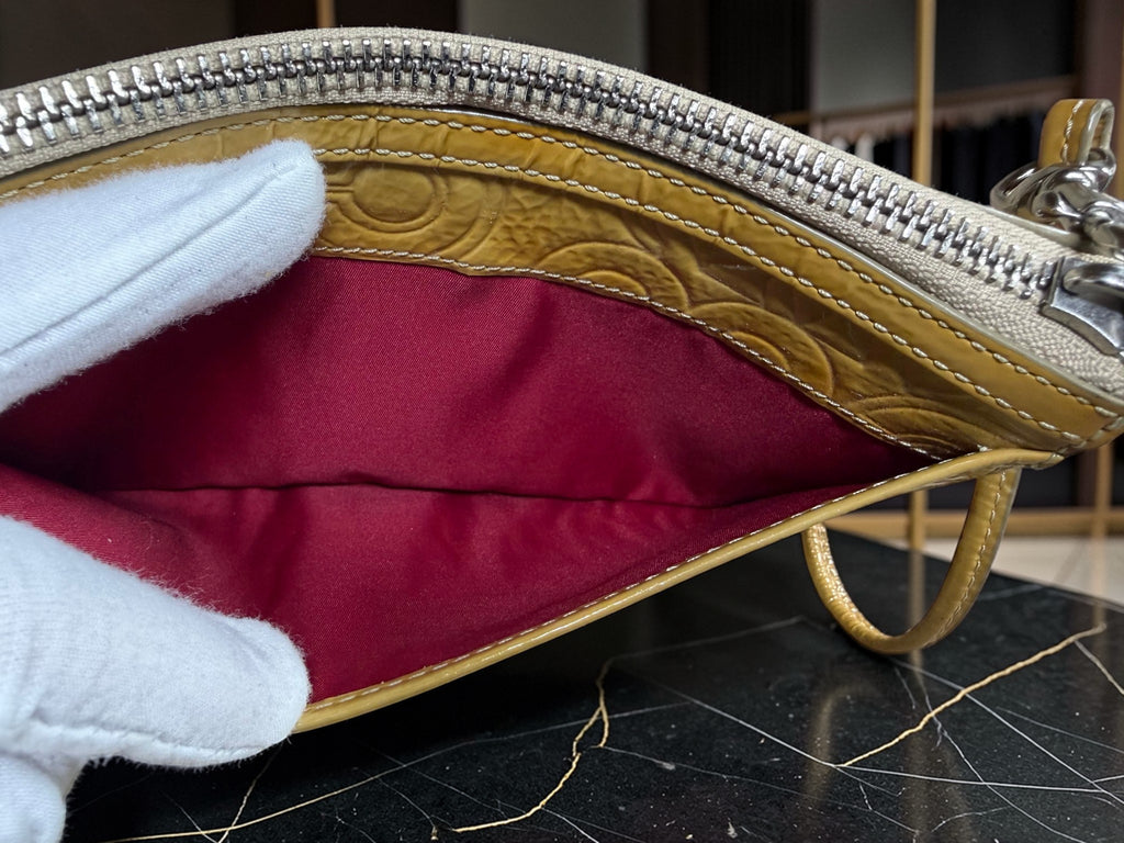 Grand porte-monnaie de poignet Coach Poppy en cuir verni jaune moutarde avec motif « C » embossé