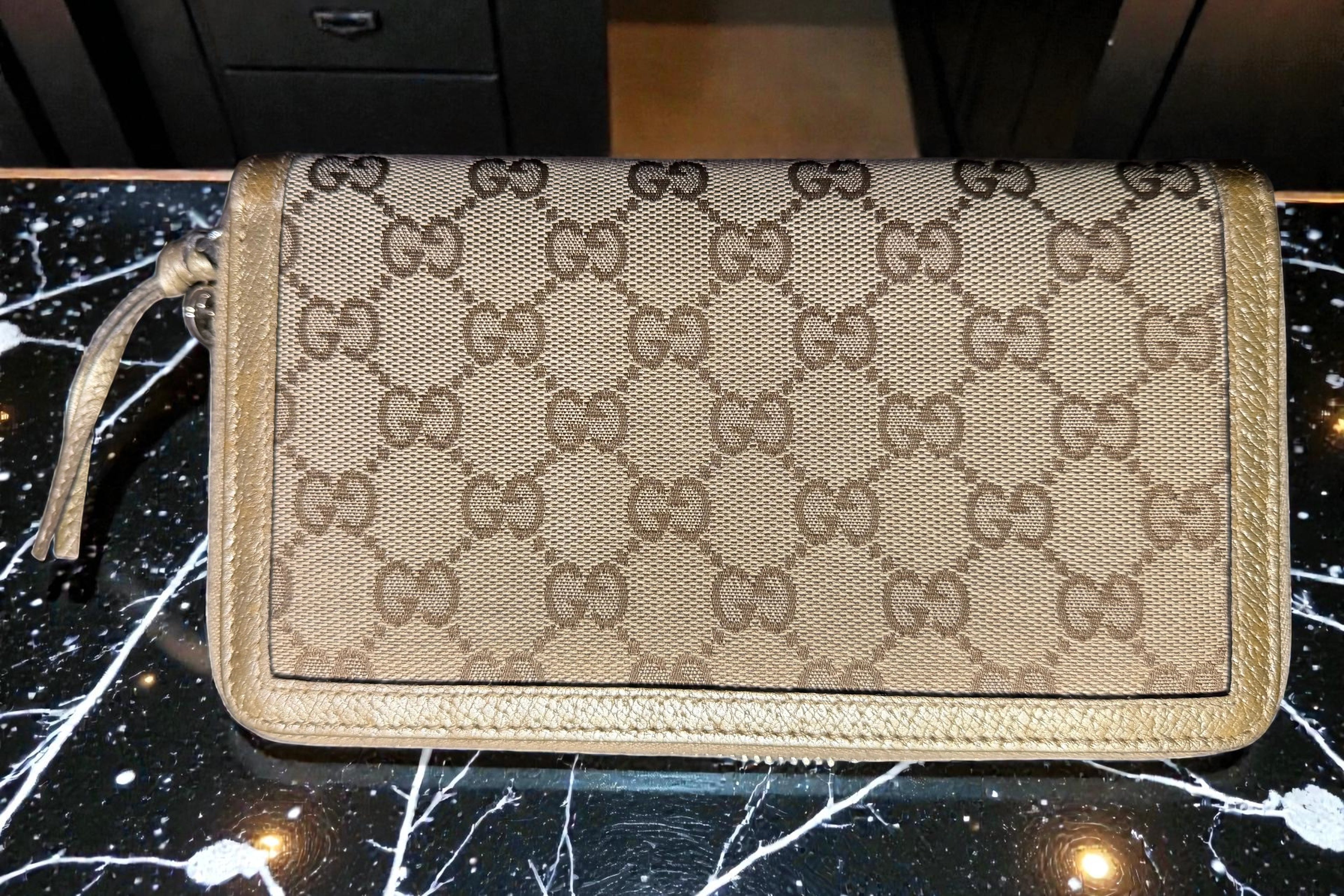 Gucci wallet with monogram pattern on a dark background